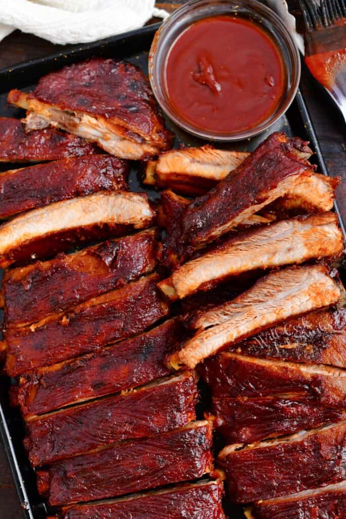 oven ribs on baking sheet with side of bbq sauce