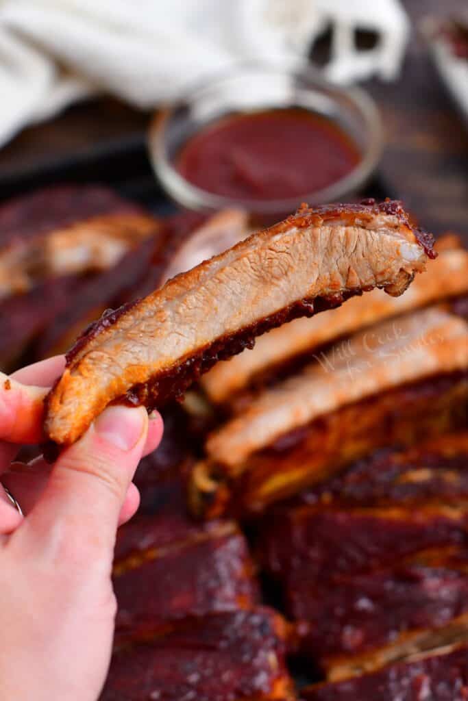 close up photo of woman's hand holding juicy spare rib