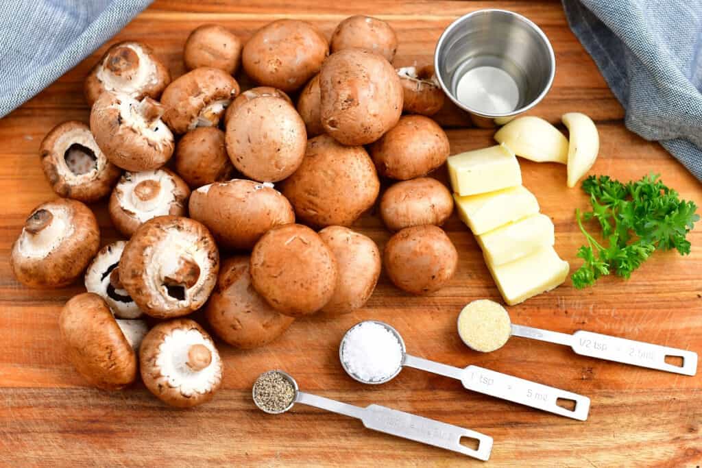 clean cremini mushrooms, butter, parsley and seasonings on cutting board
