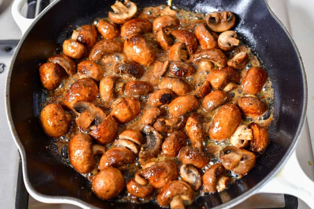 mushrooms being cooked in a skillet with butter