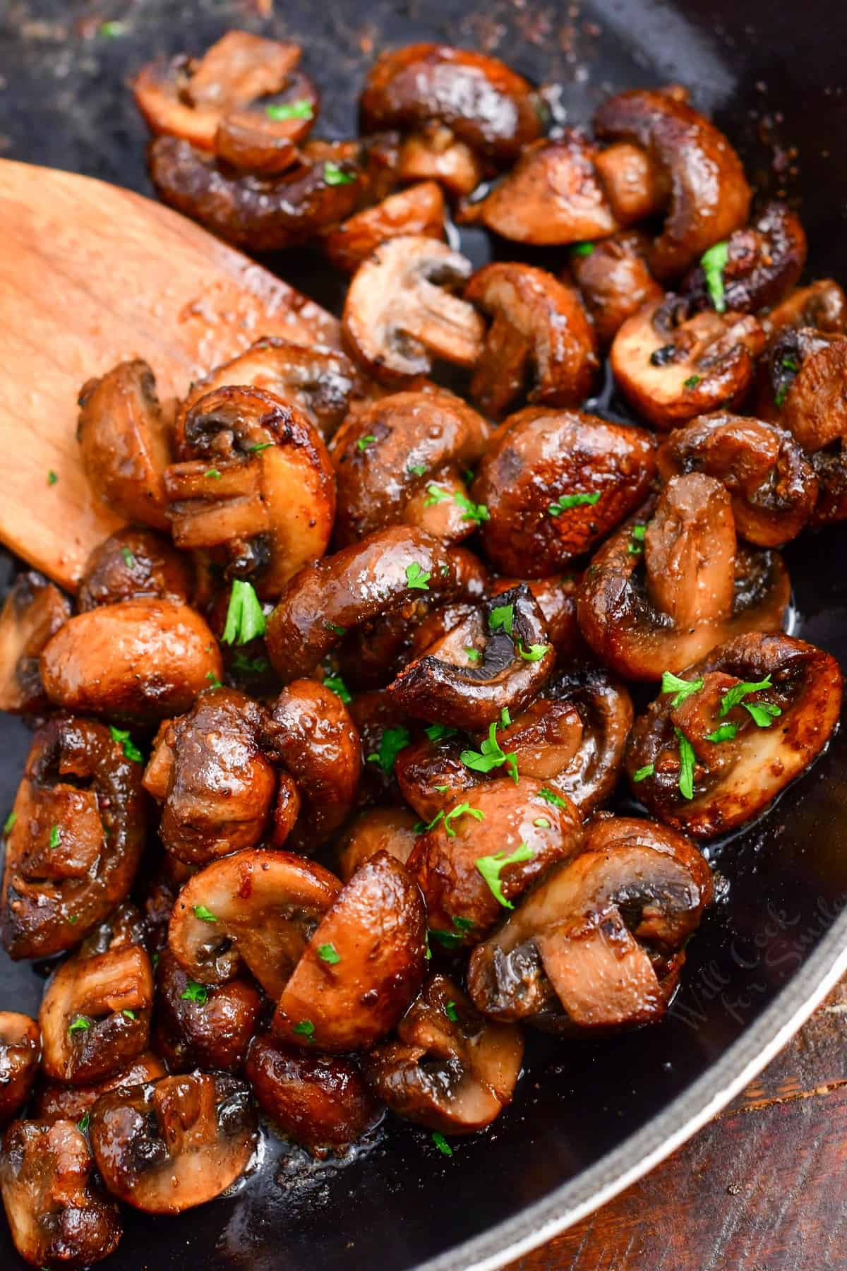 finished bright sauteed mushroom halves in a skillet topped with parsley.
