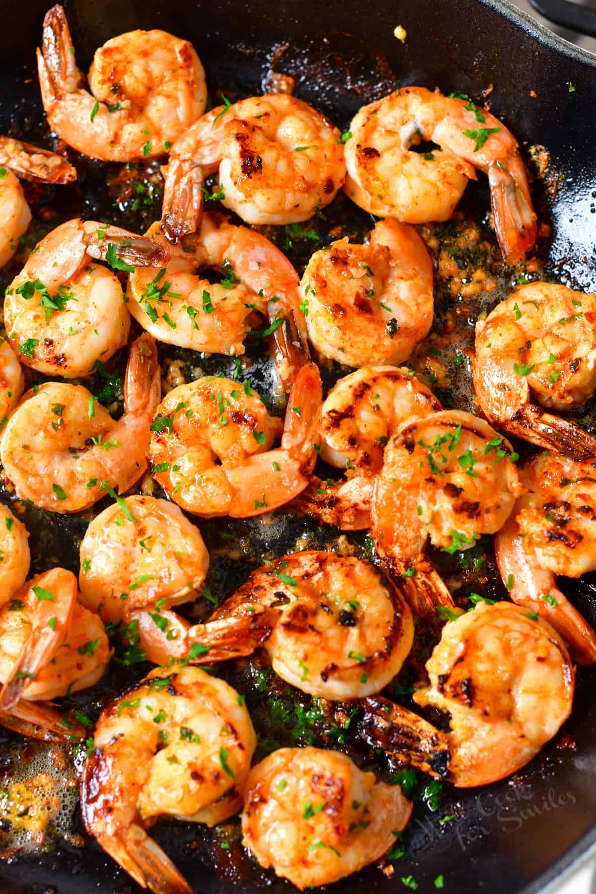 several sautéed shrimp in seasoning cooking in a skillet.
