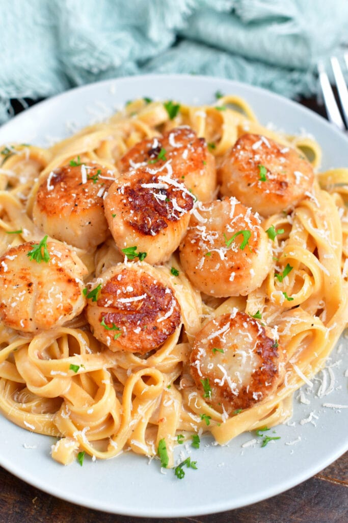 seafood pasta on a white plate with a blue cloth in the background