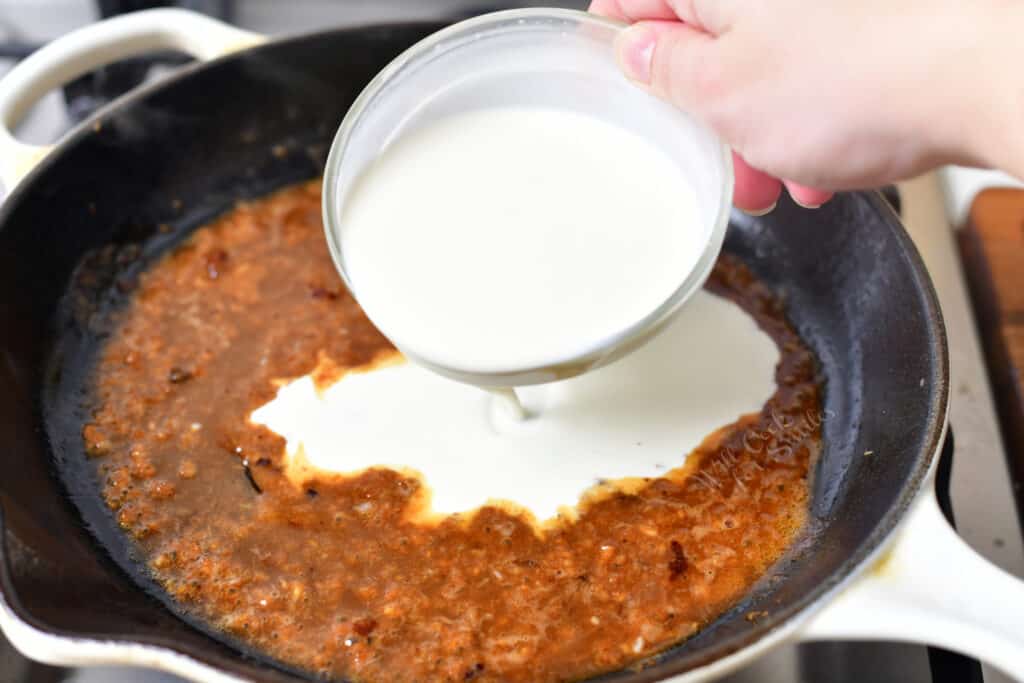 pouring heavy cream into mixture of butter, garlic, and stock
