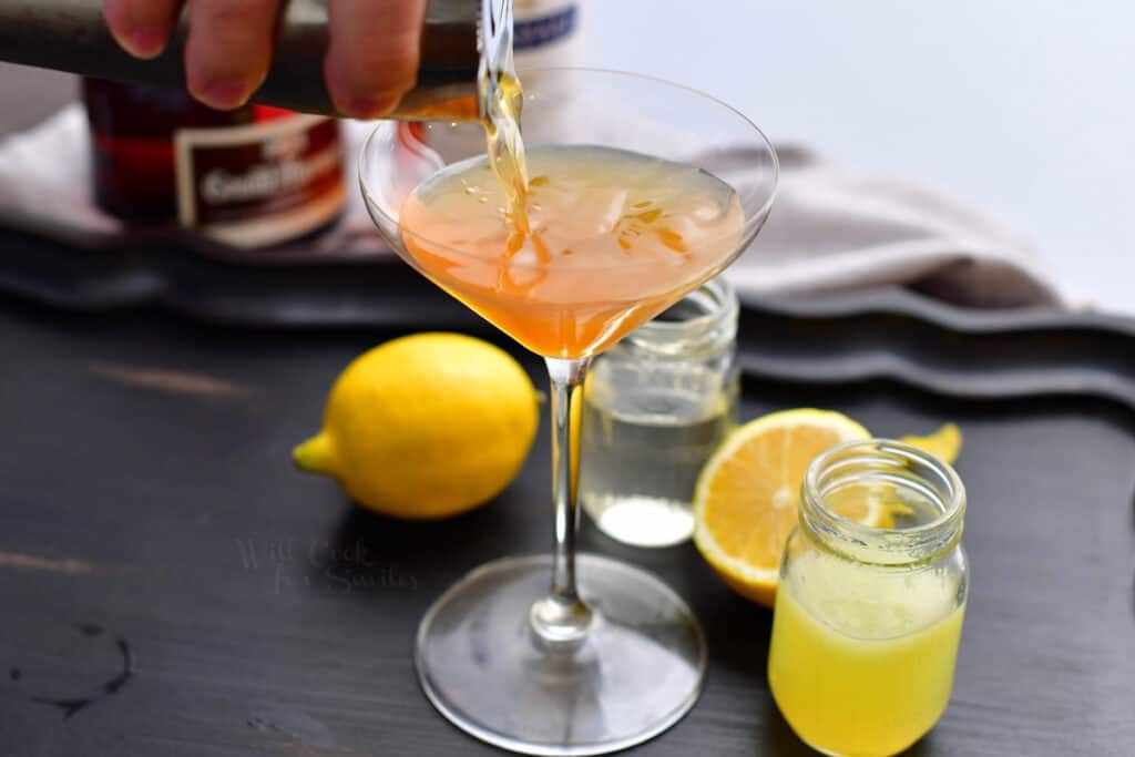 pouring in cocktail out of a shaker and into the martini glass