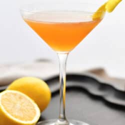 side view of a tall martini glass with orange colored Sidecar cocktail