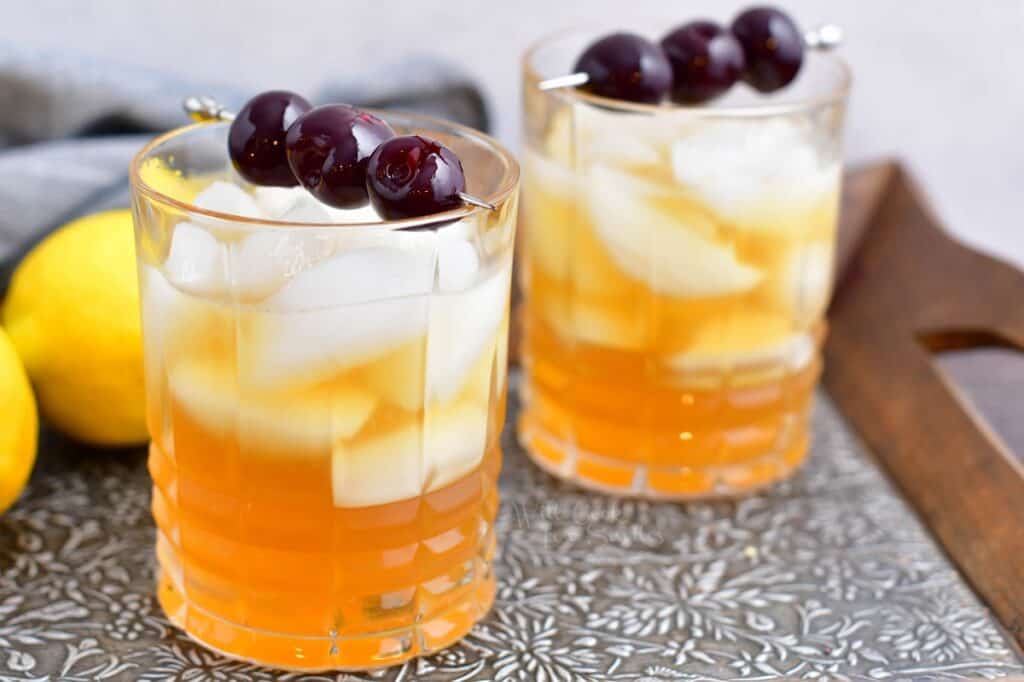 To amaretto sours are placed on a metal surface. 