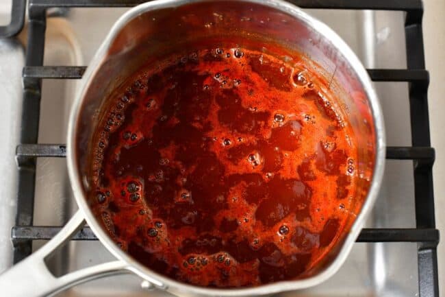 Barbecue sauce is being heated up in a large metal sauce pot.