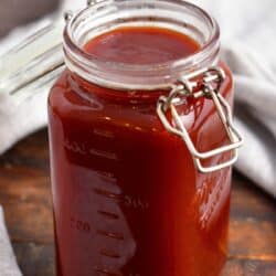 A jar of barbecue sauce is placed on a wooden surface.