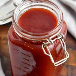 An open mason jar is filled with red BBQ sauce.