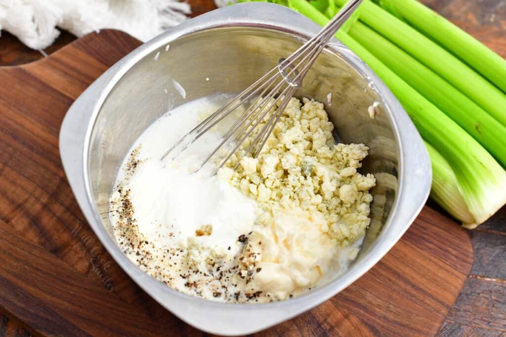 All ingredients for blue cheese are placed in a large mixing bowl with a whisk.