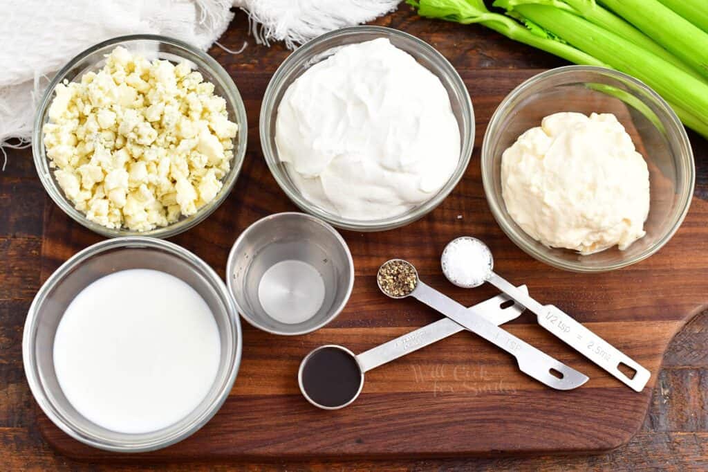 The ingredients for blue cheese dressing are spread out on a wooden cutting board.
