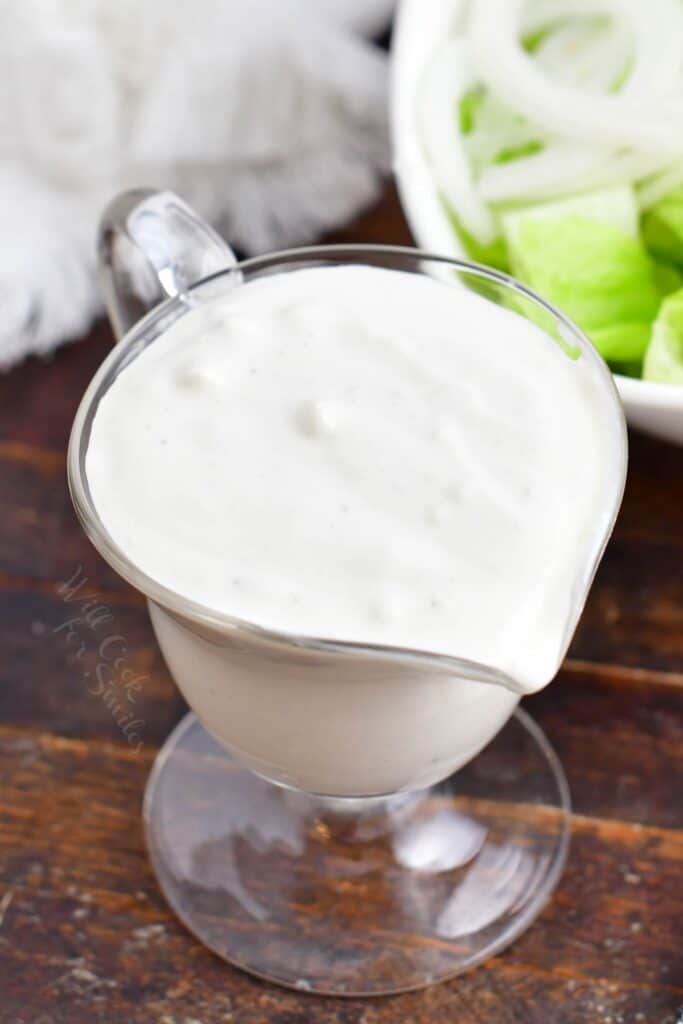 A small glass container is filled with blue cheese dressing. 