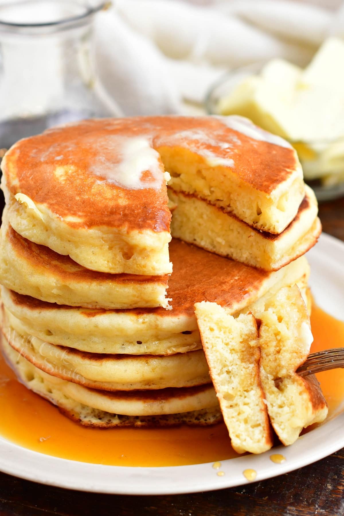 A bite sized portion of pancakes has been taken from the stack. 