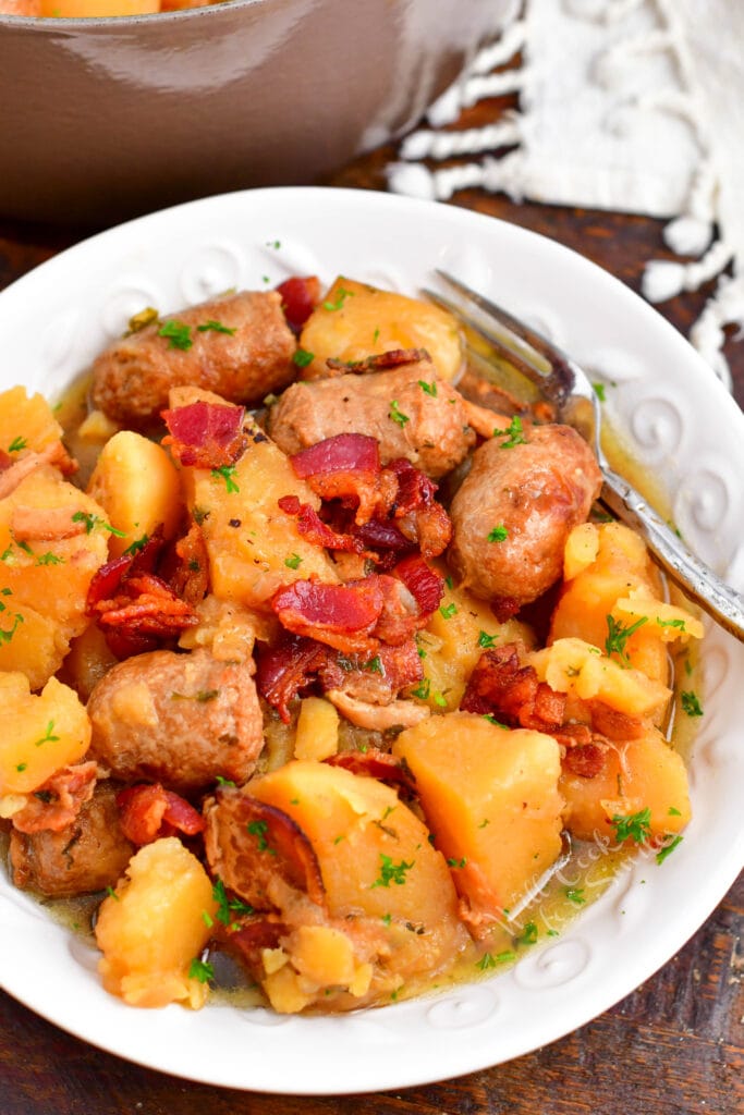 A white plate contains a serving of Dublin coddle.