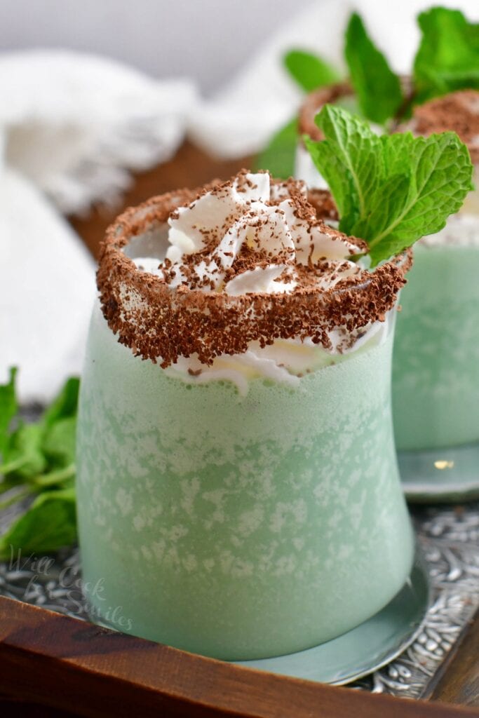 A glass of grasshopper cocktail is garnished with chocolate shavings and a mint leaf.