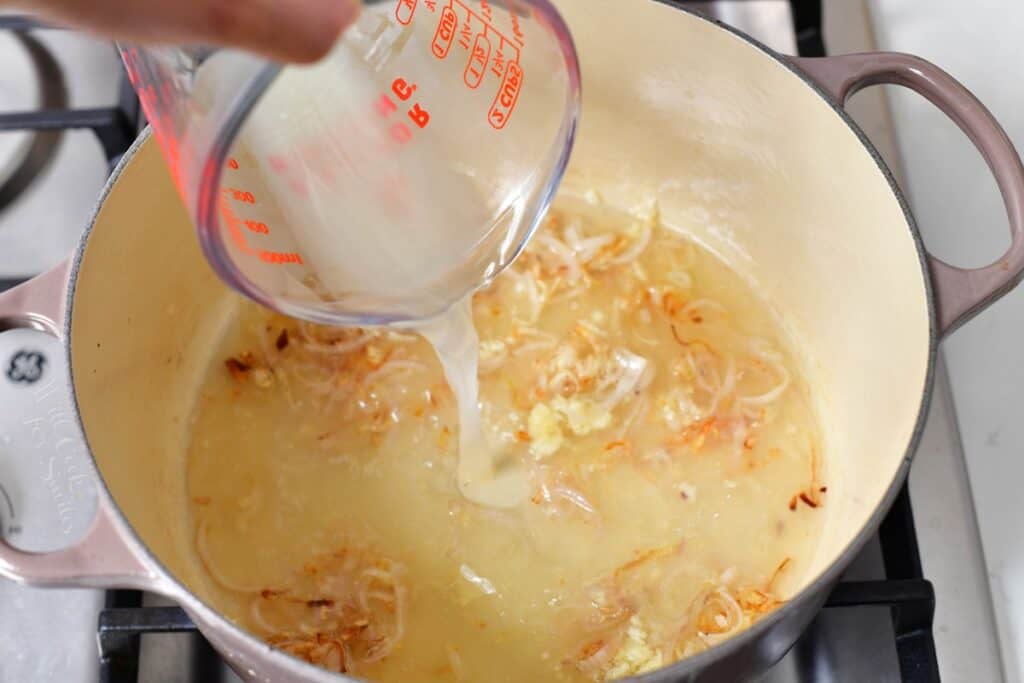 Pasta water is being poured in to a pot. 