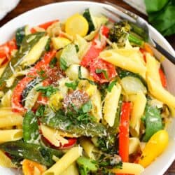 A bowl of pasta primavera is topped with grated parmesan.