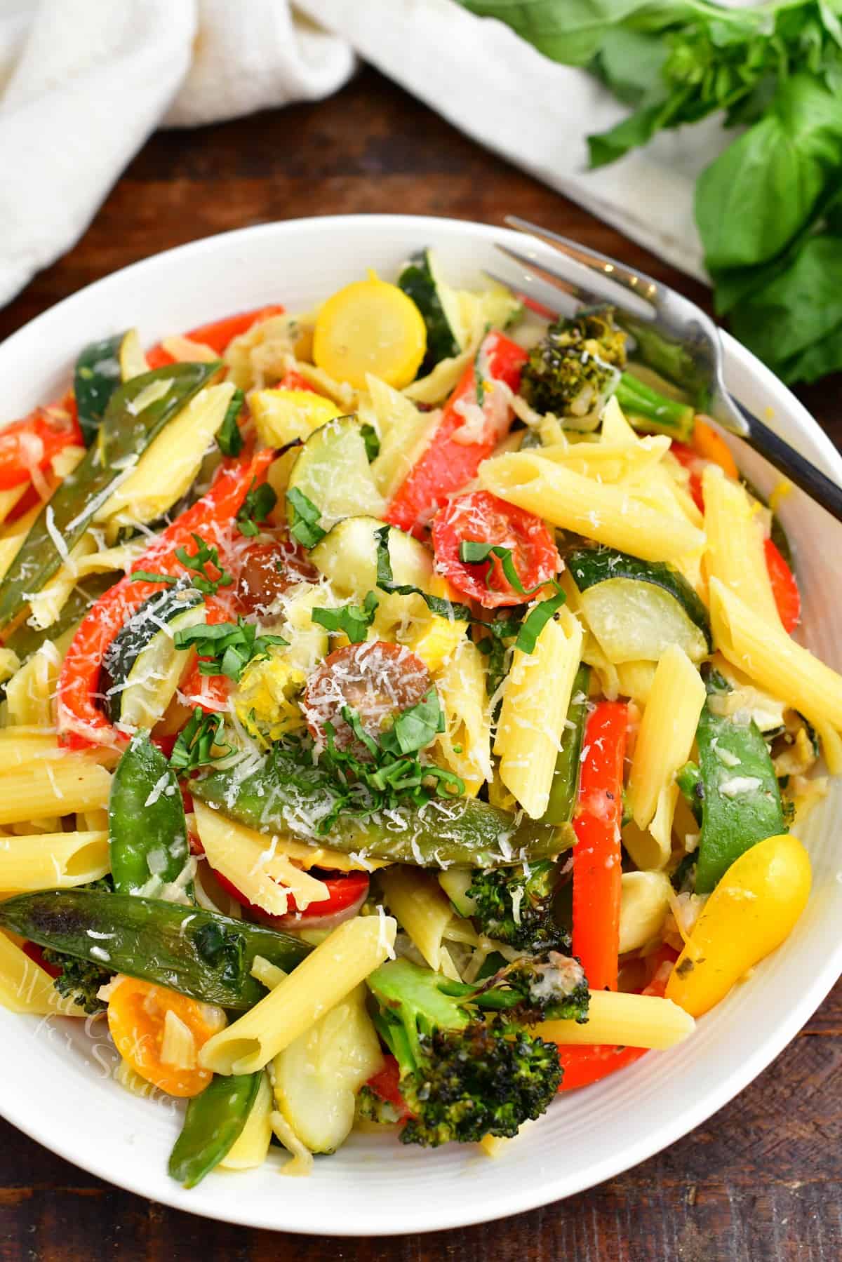 A bowl of pasta primavera is topped with grated parmesan.