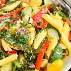 A white plate contains a large portion of pasta primavera.