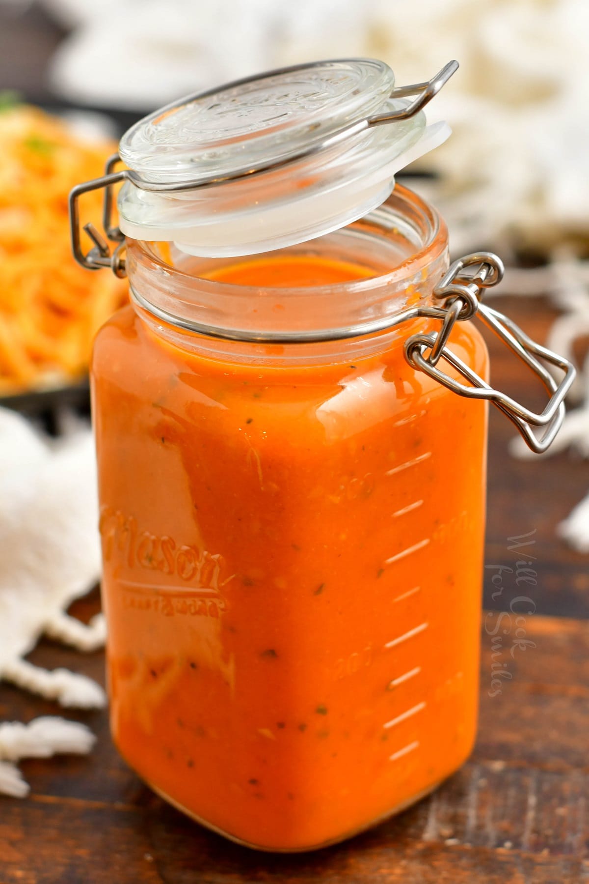 Pomodoro sauce in a glass jar with spaghetti on a background