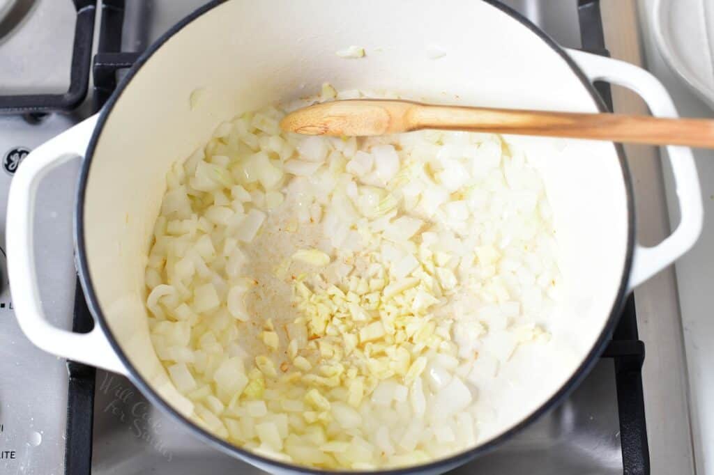 diced onions and garlic in a white Dutch oven