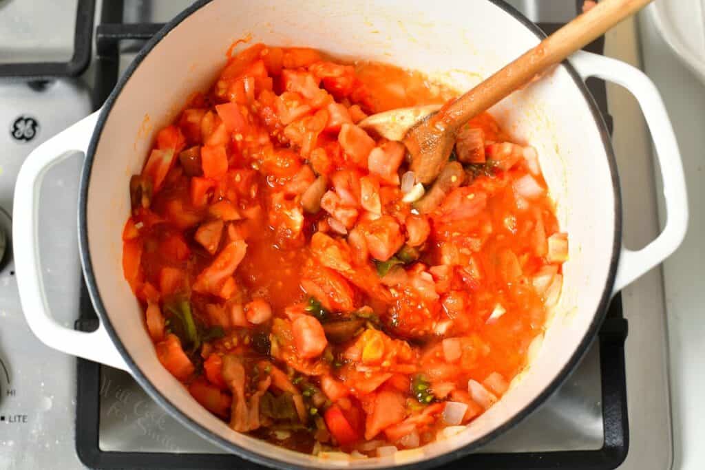diced vegetables in a white Dutch oven with wooden spoon