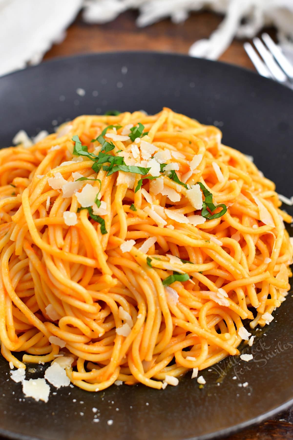 spaghetti coated in Pomodoro sauce on a dark plate with Parmesan and basil
