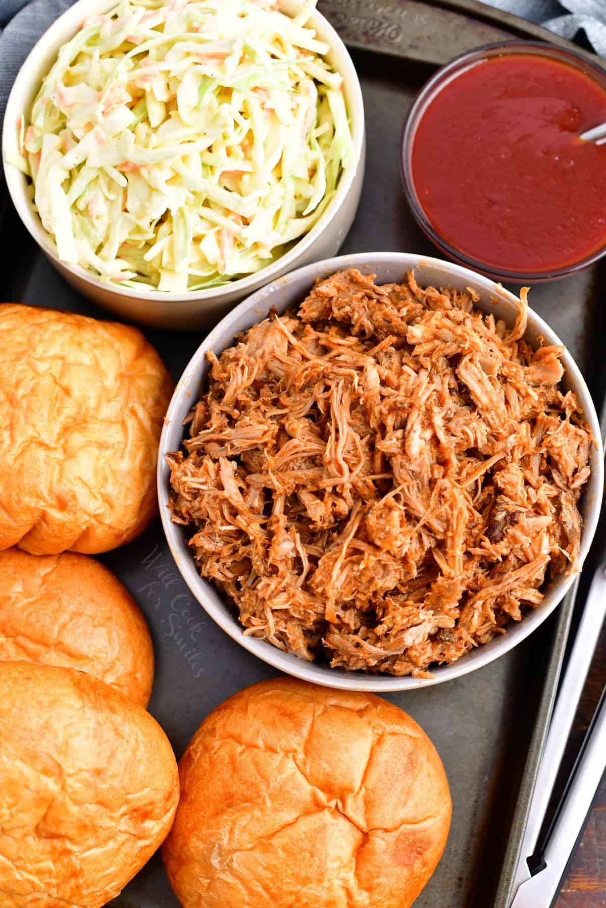 The ingredients for pulled pork sandwiches are presented on a metal surface. 