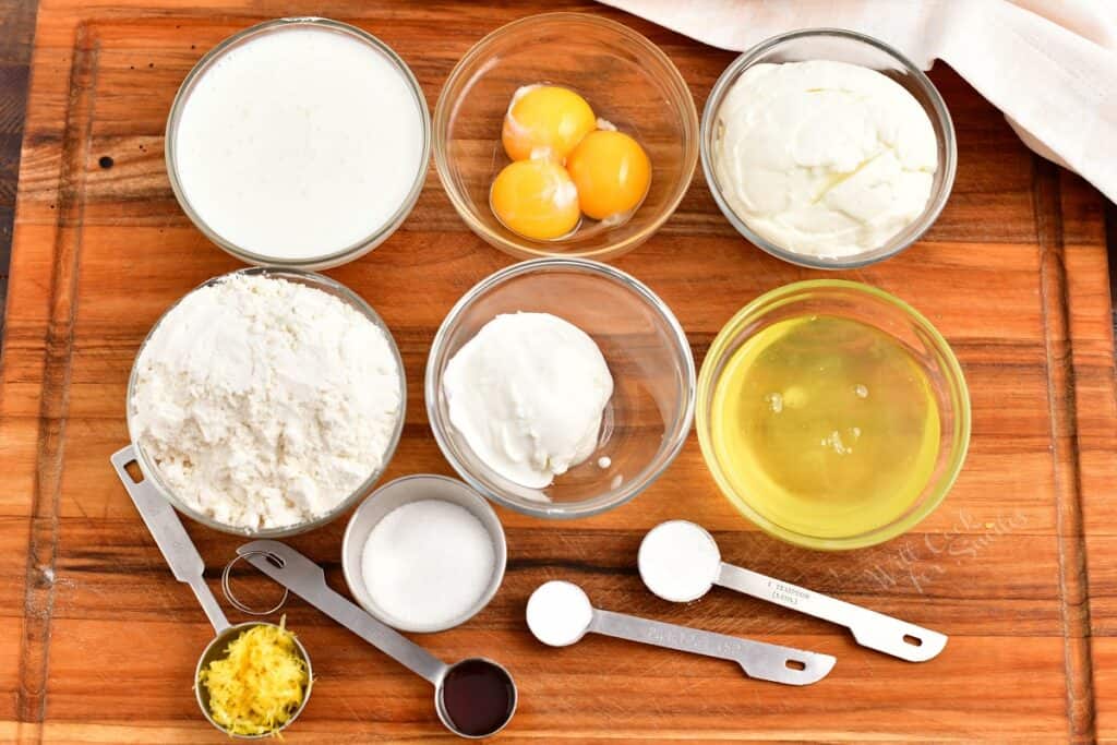 The ingredients for ricotta pancakes are placed on a wooden surface.