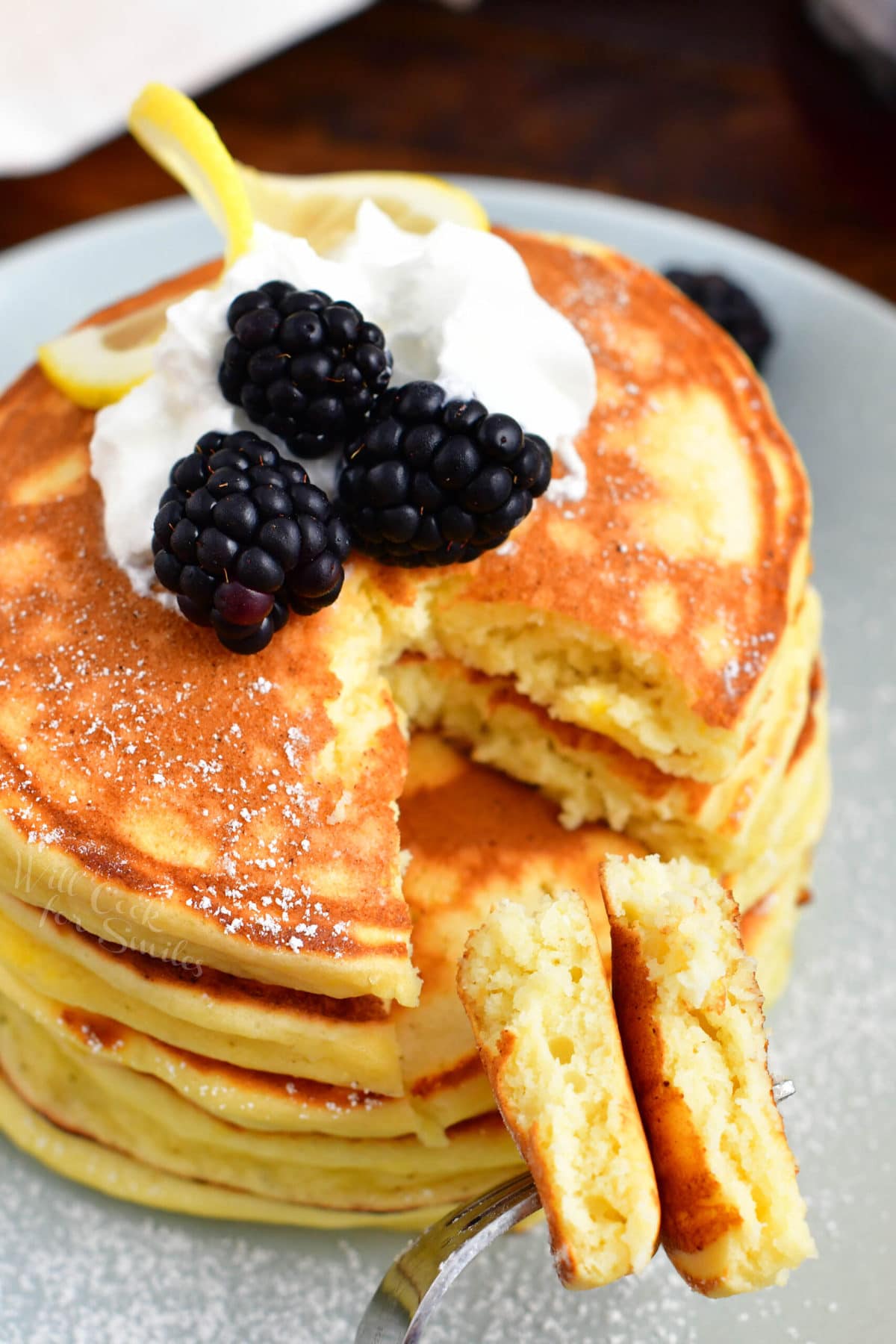 A small bite sized piece of pancake has been cut out of the stack.