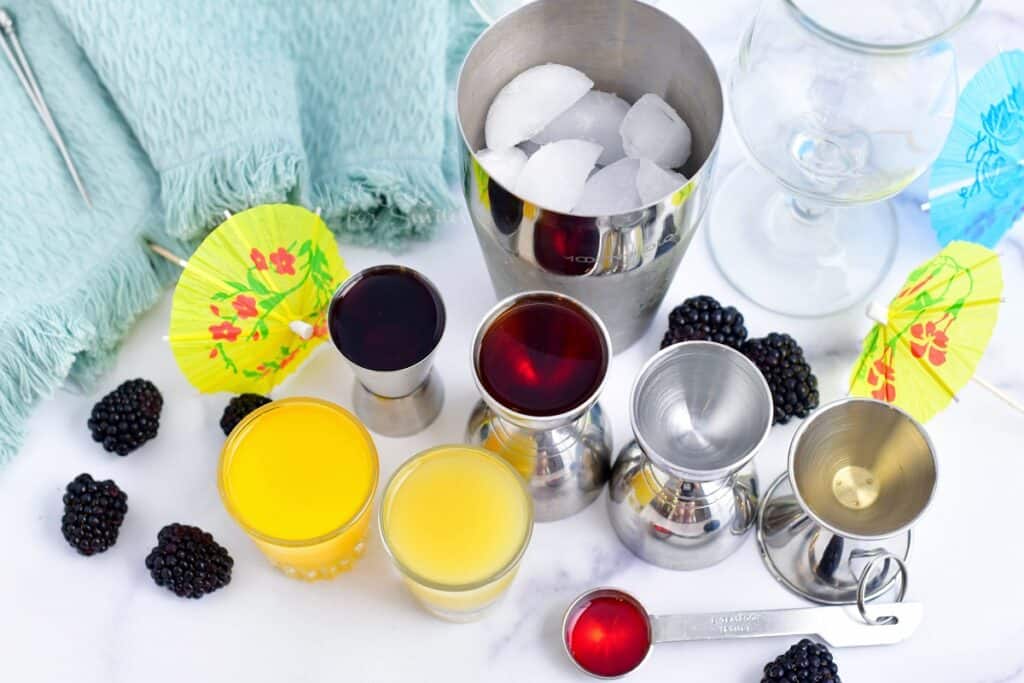 The ingredients for a rum runner are placed on a white surface.