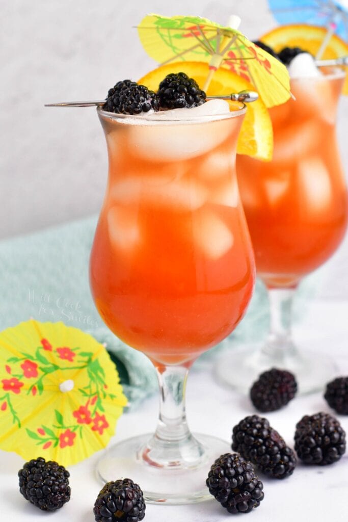 A handful of blackberries are scattered around two rum runners.