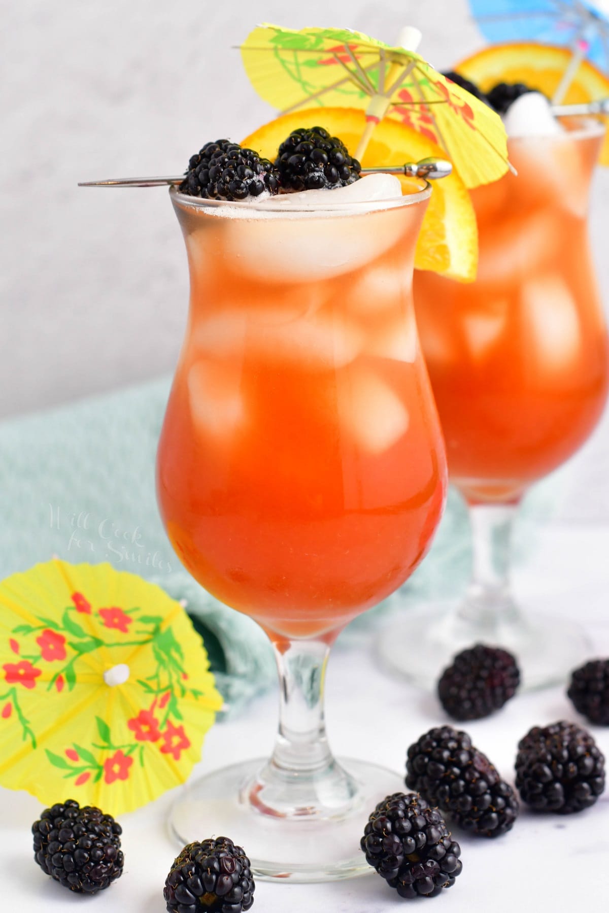 A handful of blackberries are scattered around two rum runners. 