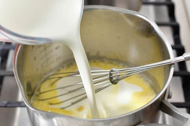 pouring heavy whipping cream into the pot with butter and flour