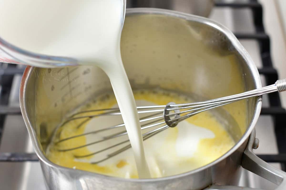 pouring in heavy whipping cream into the sauce pot.