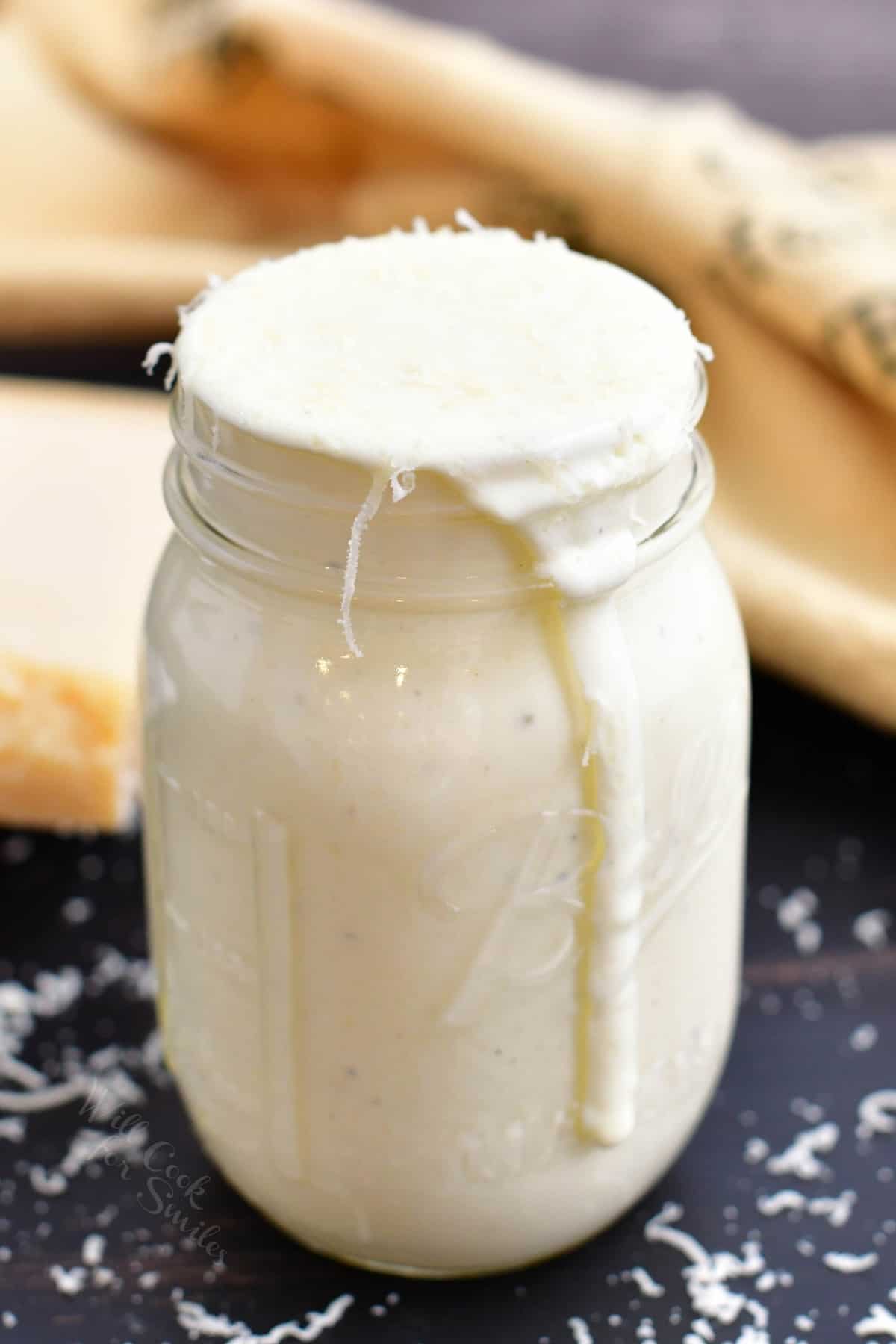 front side view of alfredo sauce in a mason jar. 
