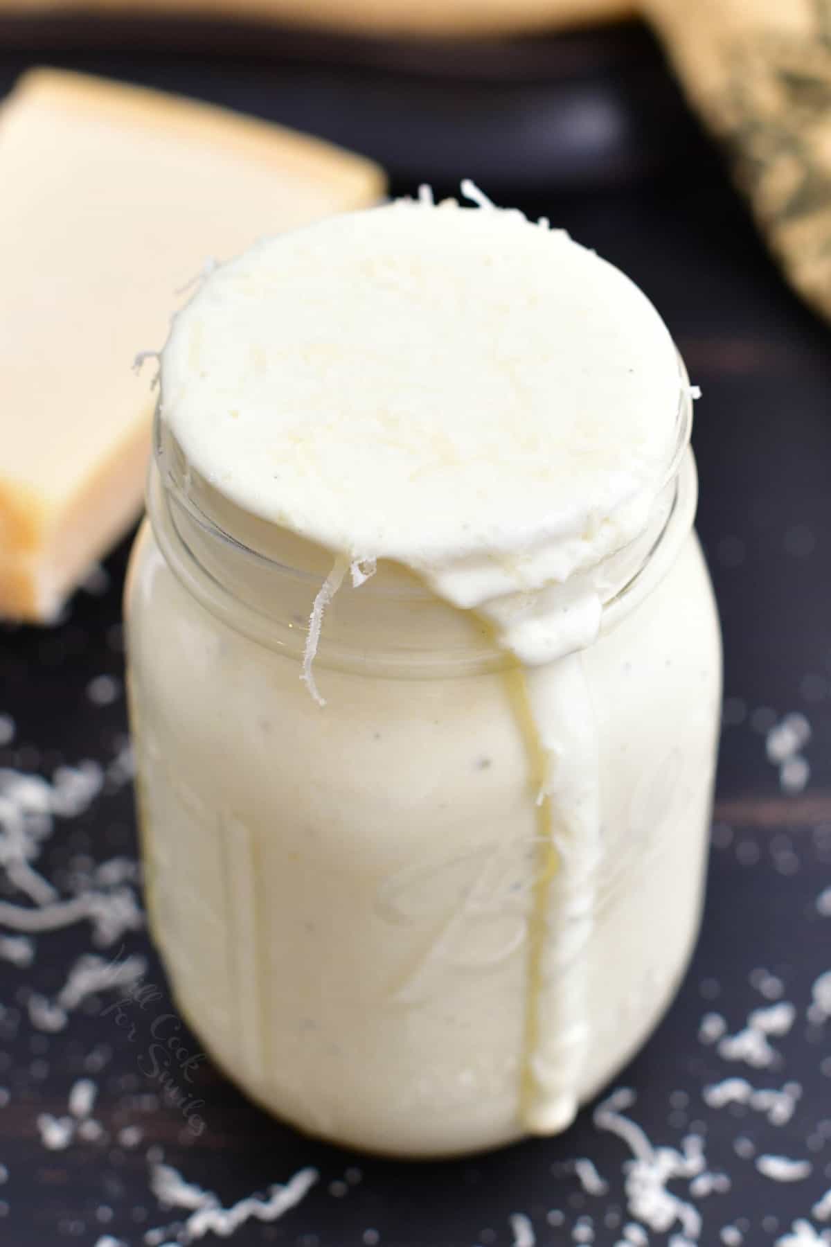 top view of Alfredo sauce in mason jar with some pouring out.