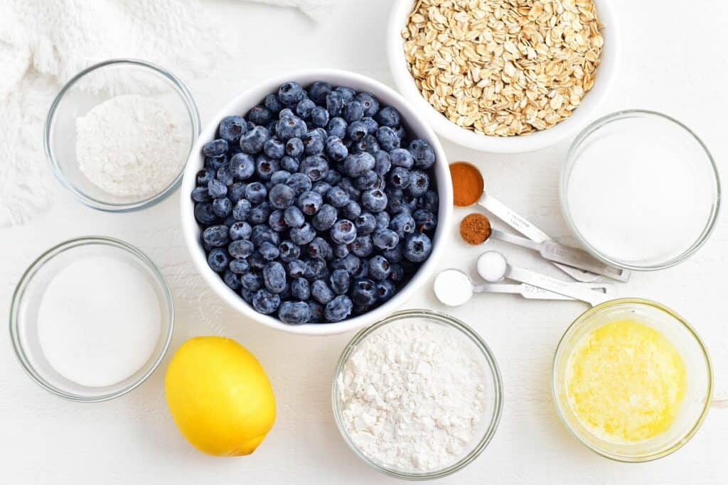 The ingredients for blueberry crisp are placed on a white surface.