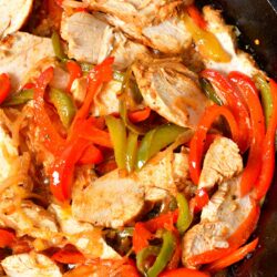 Chicken and veggies are mixed in the same skillet.