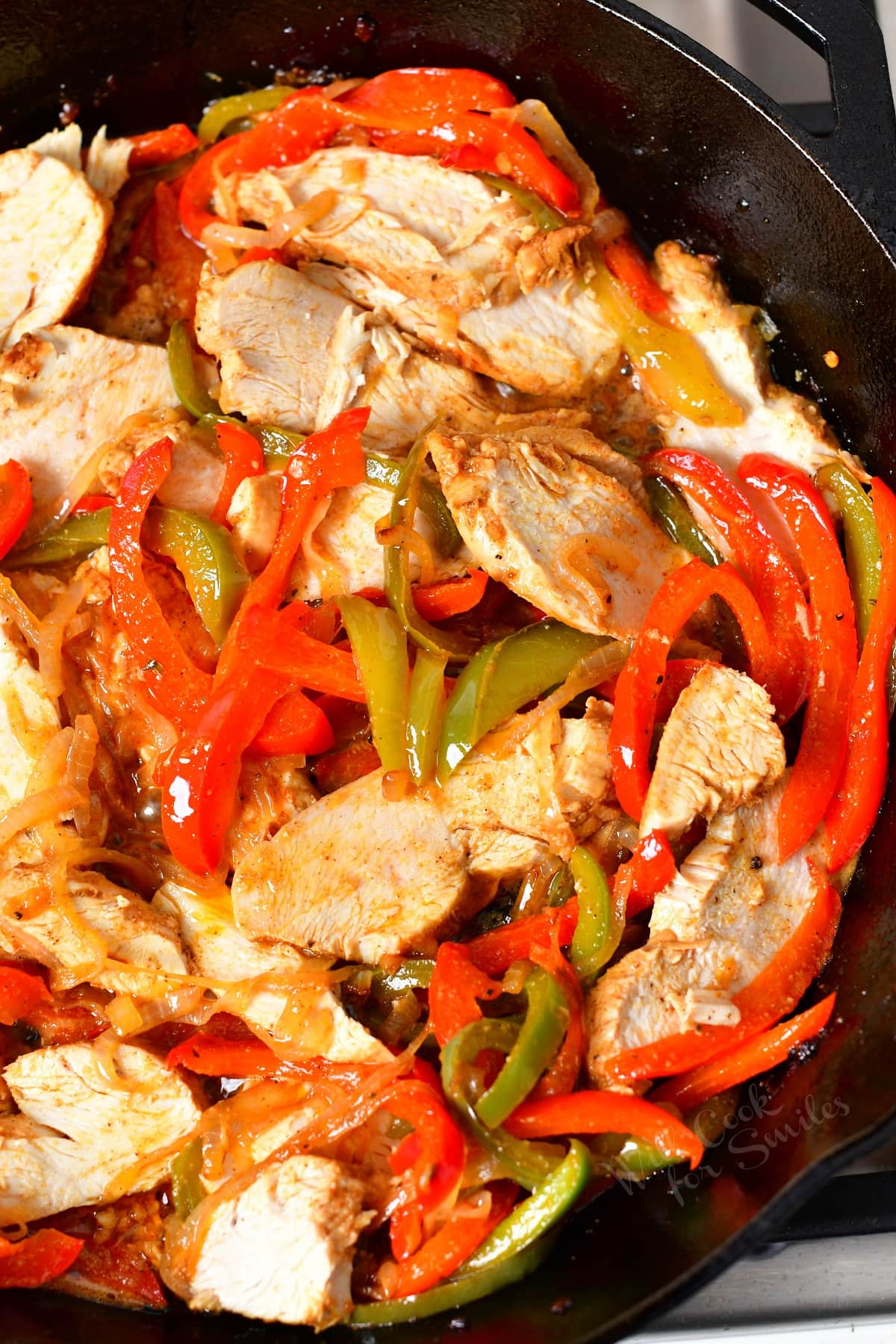 Chicken and veggies are mixed in the same skillet.