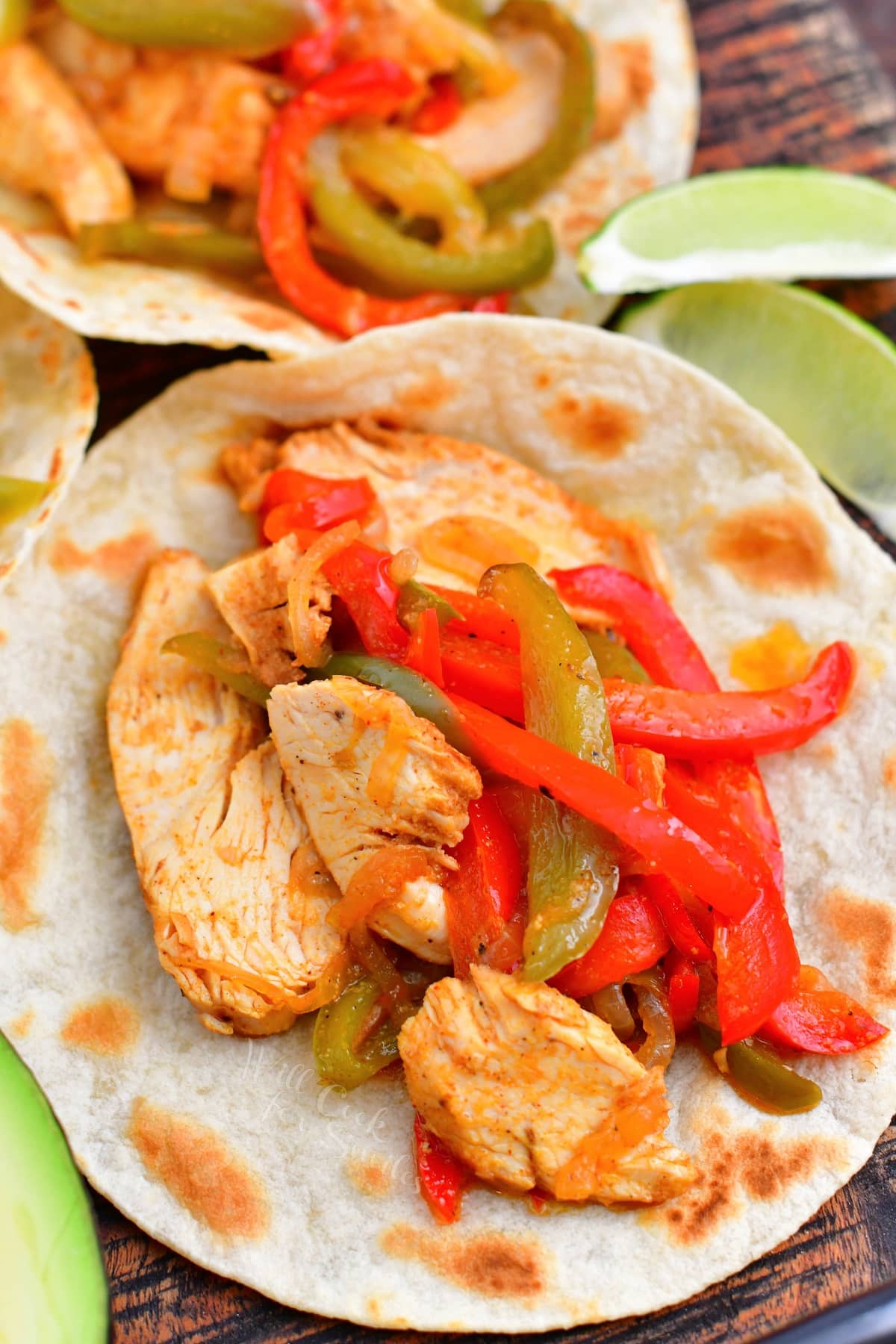 Chicken fajitas are in open flour tortillas. 