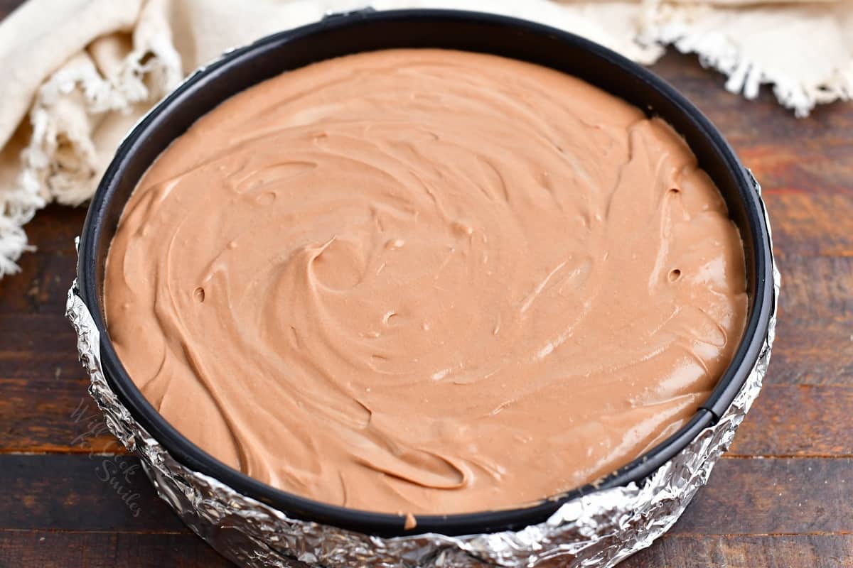 Chocolate cheesecake is uncooked in a springform pan. 