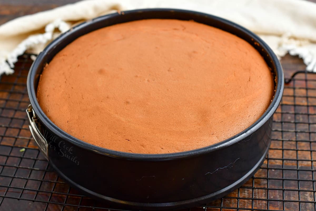 A baked cheesecake is presented on a wire cooling rack.