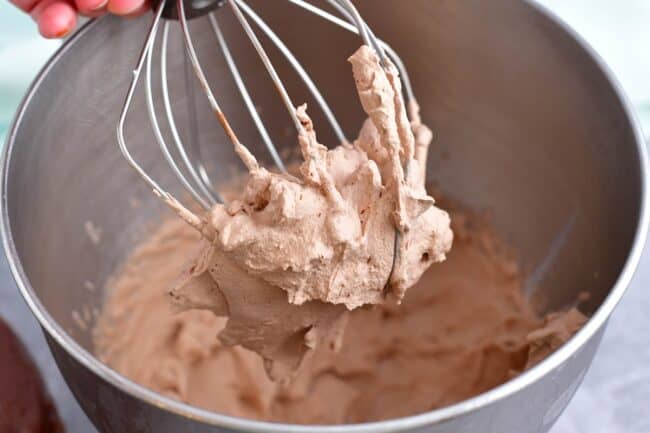 Chocolate whipped cream is being whipped with a whisk.