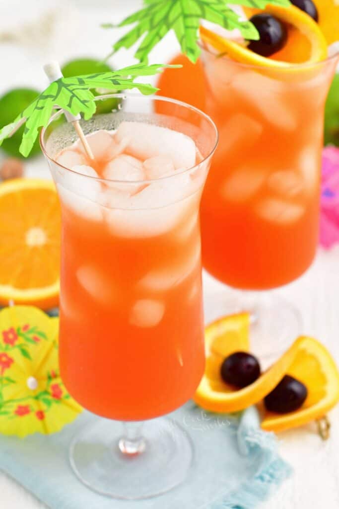 Ice cubes have floated to the top of a glass filled with rum punch.