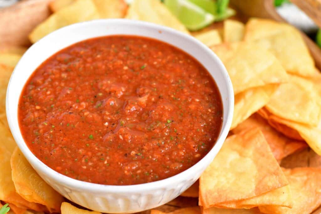 Salsa is placed next to tortilla chips in a white bowl.