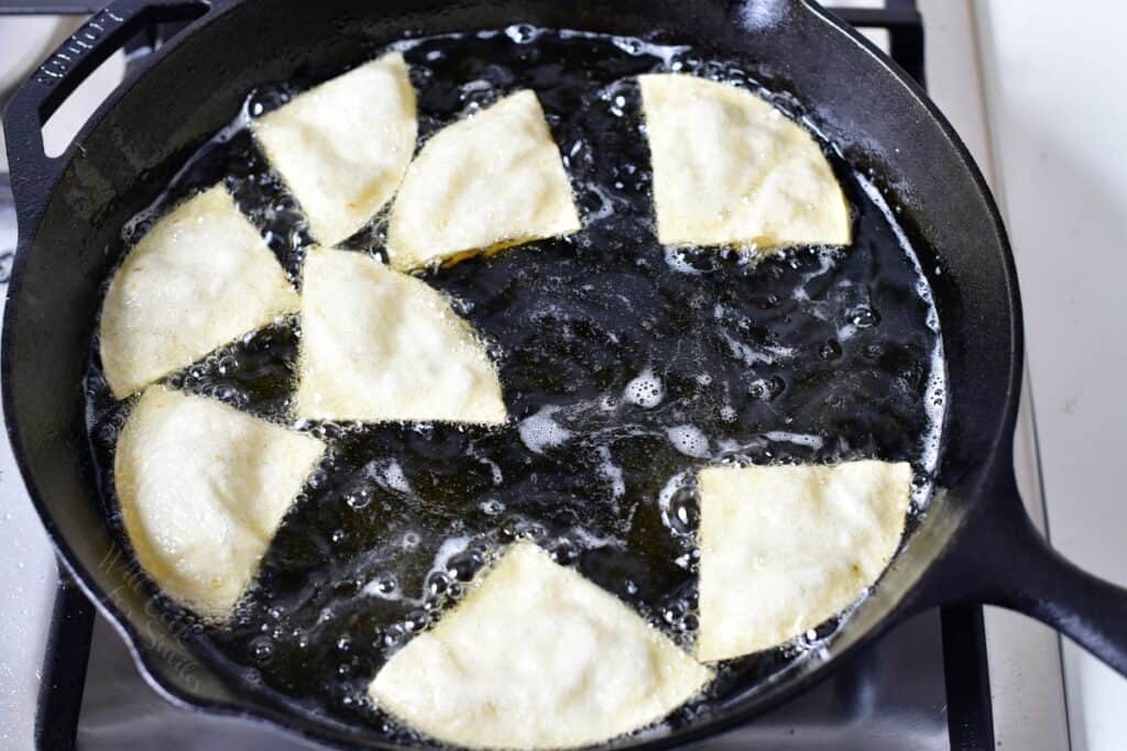 Uncooked chips are being cooked in oil.