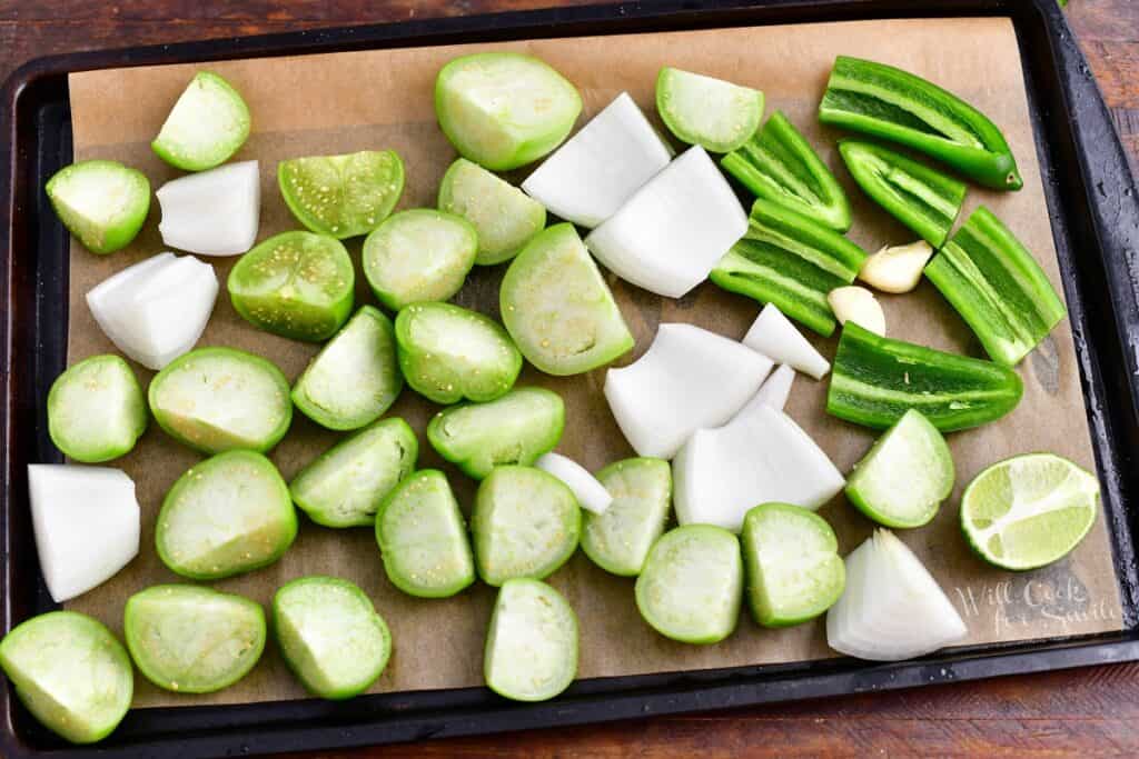 The uncooked ingredients for salsa verde are placed on a baking sheet.