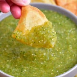 A chip is scooping a bite sized portion of salsa from the bowl.